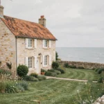 Maison normande en pierre avec volets blancs à louer en bord de mer en Seine-Maritime, vue extérieure grand angle